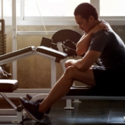 Person sitting on a bench holding neck possibly due to discomfort.