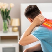 A person sitting on bed touching back of neck