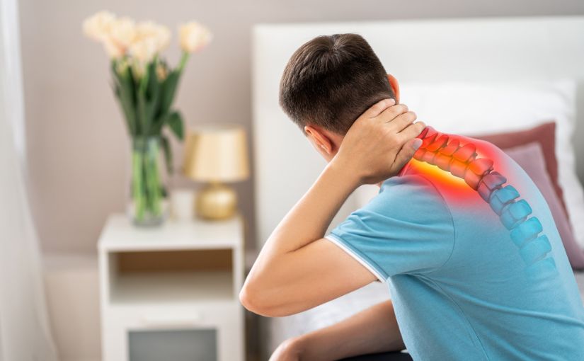 A person sitting on bed touching back of neck