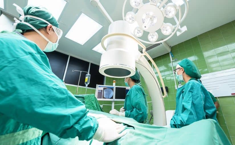 A team of surgeons in green scrubs collaborates in an operating room, engaged in a surgical procedure.
