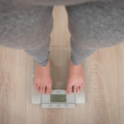 A person stands on a scale, feet firmly on the floor, measuring their weight