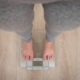 A person stands on a scale, feet firmly on the floor, measuring their weight