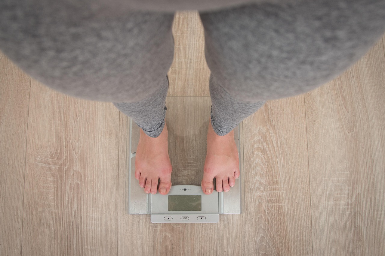 A person stands on a scale, feet firmly on the floor, measuring their weight