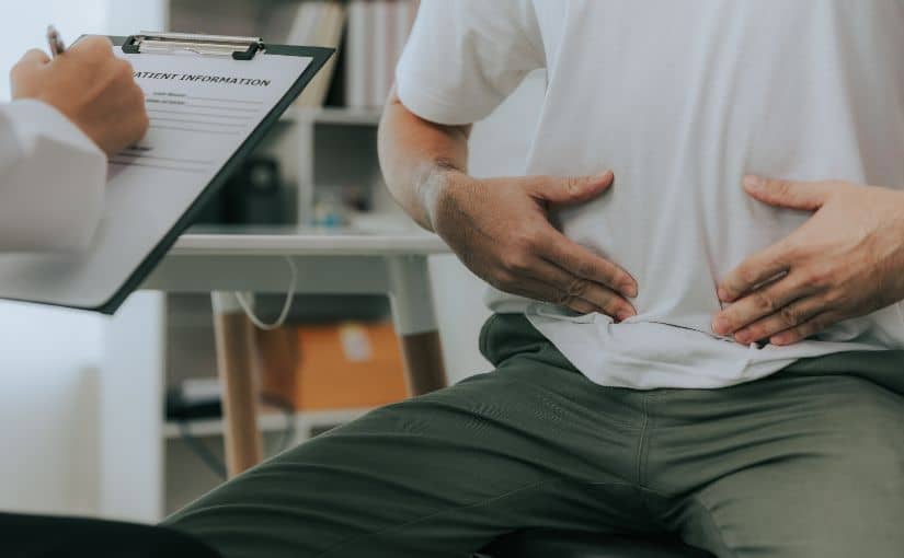A doctor performing a physical examination on a patient's abdomen in a clinical setting.