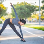 A person dressed in a grey top and leggings is stretching, demonstrating a yoga pose for improved flexibility