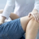 A chiro doctor examines a man's knee during a medical consultation in a clinical setting.