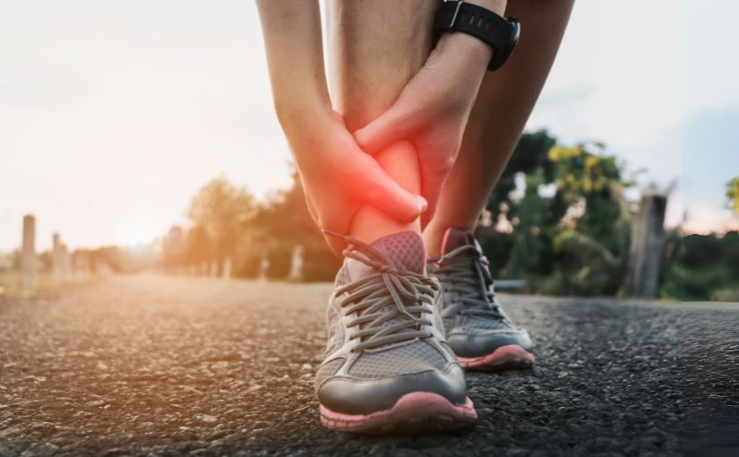 A person sitting on the roadside, holding their painful ankle, showing signs of discomfort.