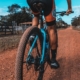 A man cycling down a dirt road surrounded by greenery and trees.