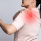 A woman grimaces, holding her shoulder in discomfort, indicating pain and distress in her expression