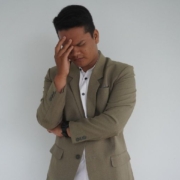 Person in a suit and white shirt holds his head, appearing stressed or deep in thought.
