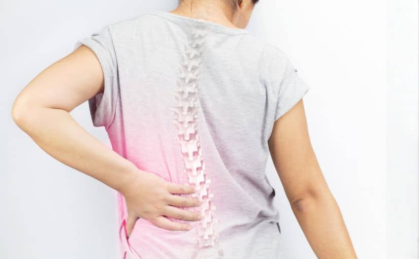 person with back pain touching their lower back