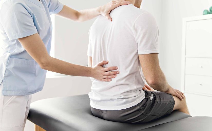 Chiro doctor assessing back of individual for pain 
