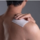 person putting medicated patch on shoulder