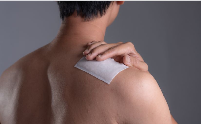 person putting medicated patch on shoulder 