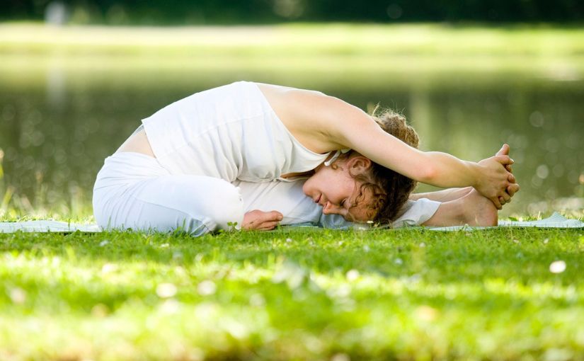 person performing stretching exercises on grass 