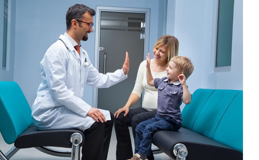 chiro doctor high fives child with mother in a clinic