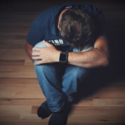 Personsitting on the floor, head in hands, expressing distress or deep contemplation.