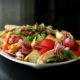 A fresh salad featuring grilled chicken, ripe tomatoes, and crisp lettuce arranged in a bowl