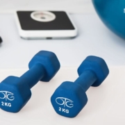 Two blue dumbbells positioned on a white surface, emphasizing their fitness purpose and bright appearance.