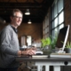 Person working at an adjustable standing desk with a computer in a modern loft office