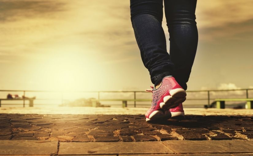 close-up shot of a person walking on a stone paved path outdoors