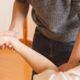 close-up shot of a practitioner wearing a grey sweater holding and examining a patient's arm and wrist during a chiropractic session.